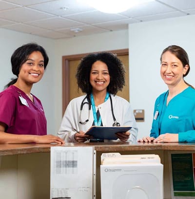 Three staff members smiling at a reception desk