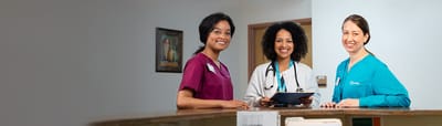 Three smiling staff members at a reception area