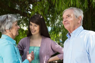 Three people engaging in conversation under a tree