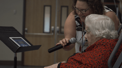 Staff member singing with a resident during an activity.