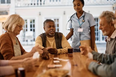 Residents engaging in a card game with staff in a common area