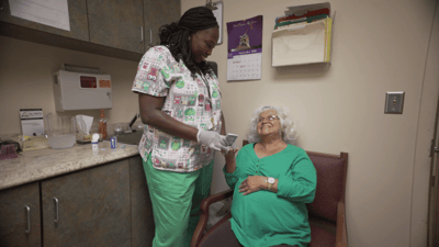 A caregiver assisting a senior woman in a private room