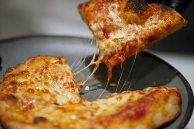 Close-up of a cheesy pizza slice being lifted