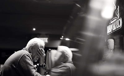 Older man with head in hands at a table