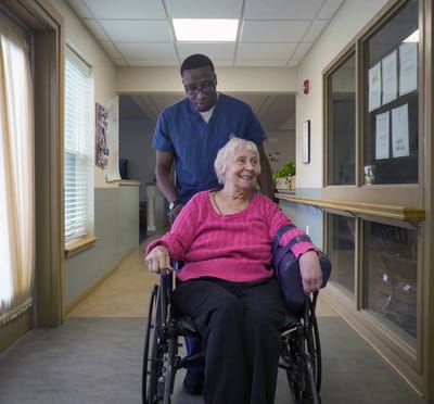 A caregiver assisting a resident in a hallway