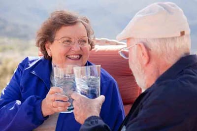 Two residents smiling and toasting with drinks