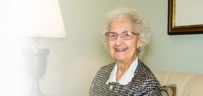 A smiling elderly woman sitting in a well-lit room