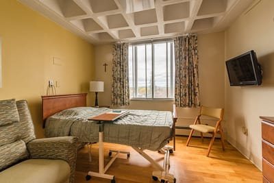 A well-furnished private resident room with a bed and a chair
