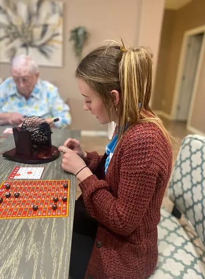 Resident and staff member playing bingo in an activity room