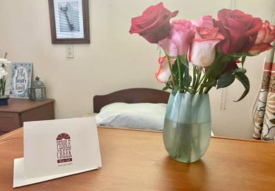 Roses in a vase next to a bedside table in a resident room
