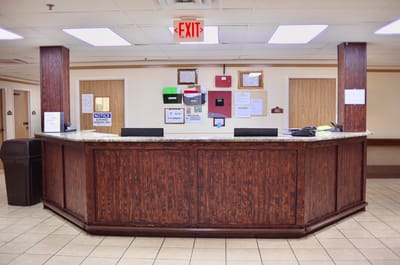 Reception area with a wooden desk and notices on walls