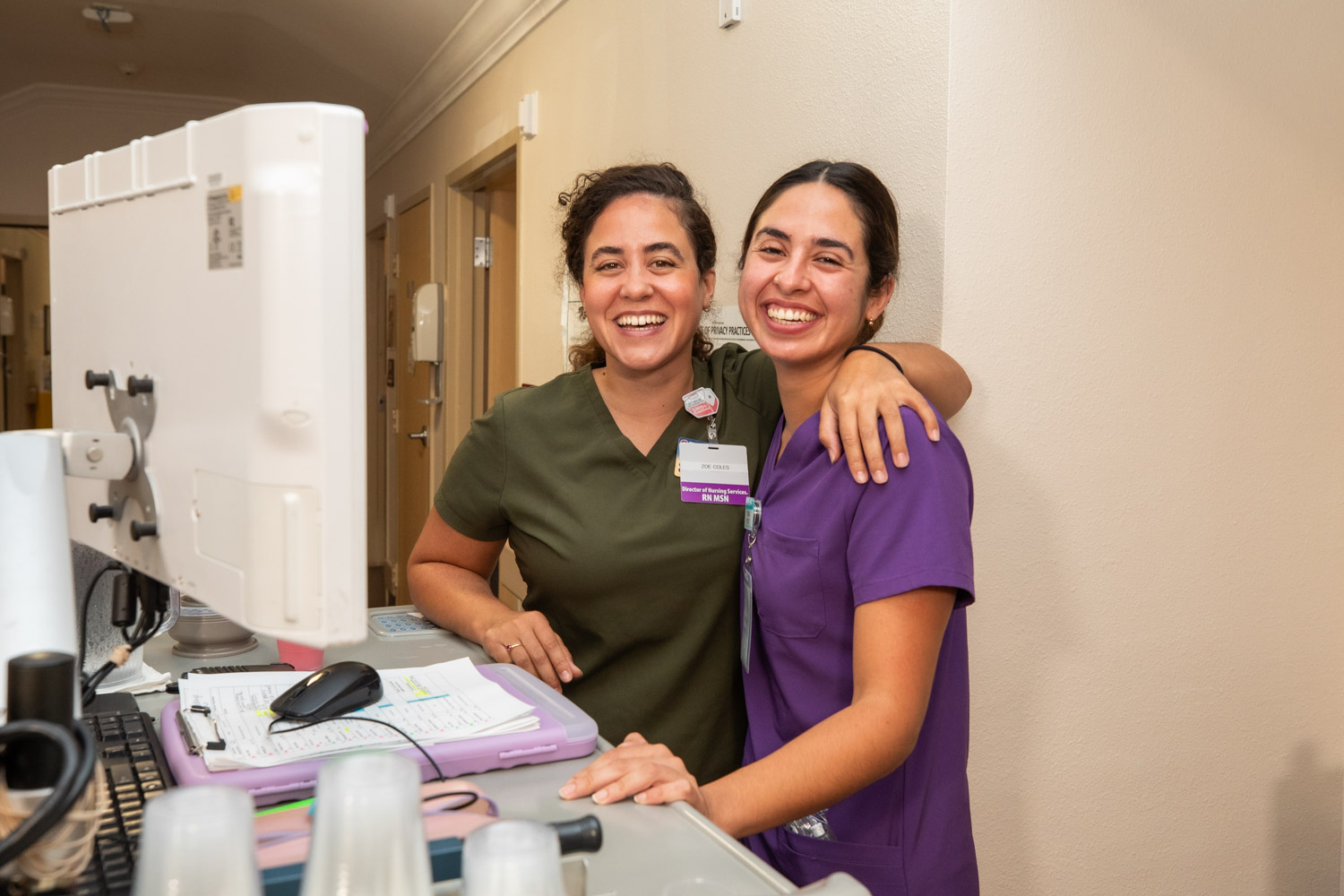 Two smiling staff members at a reception desk