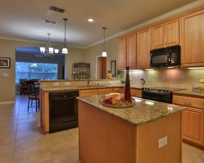 Well-lit kitchen area with wooden cabinetry and granite countertops