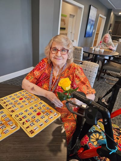Resident enjoying bingo with a flower