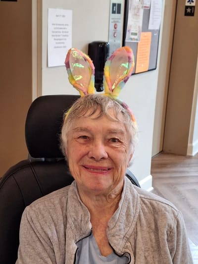 Resident smiling with colorful bunny ears in common area