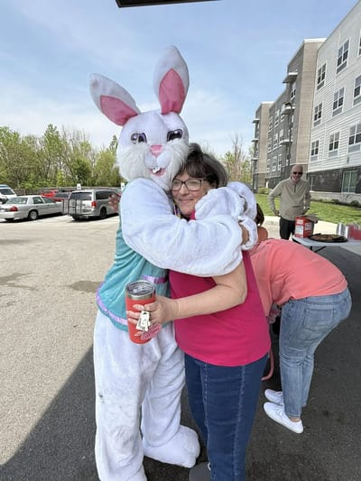 Resident hugging a costumed character outdoors