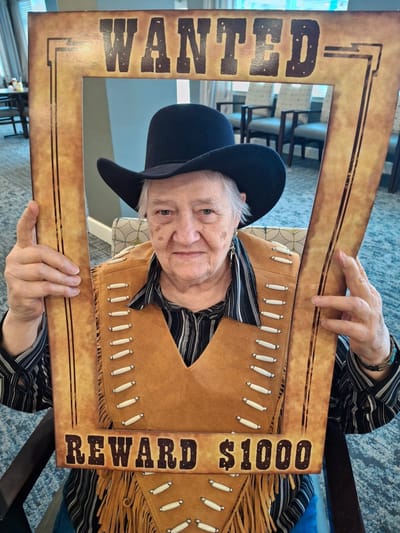 Resident dressed as a cowboy holding a wanted sign