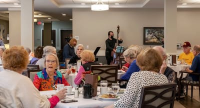 Residents enjoying a meal with live music in the dining room