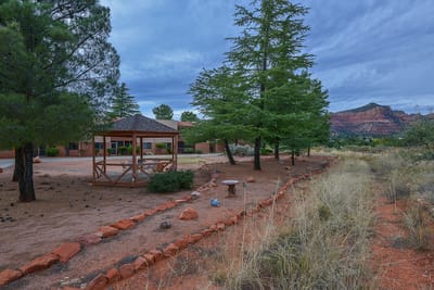 Outdoor gazebo area surrounded by trees and landscape
