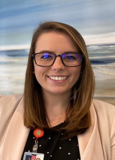 Staff member smiling in front of a decorative background