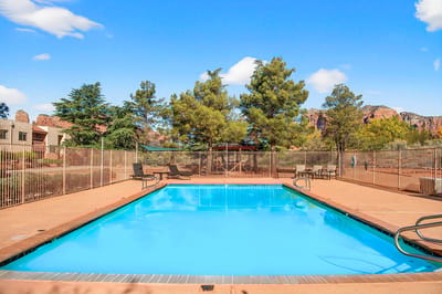 Outdoor swimming pool surrounded by trees and lounge chairs