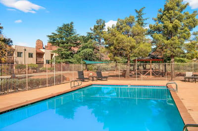 Swimming pool area with surrounding trees and lounge chairs