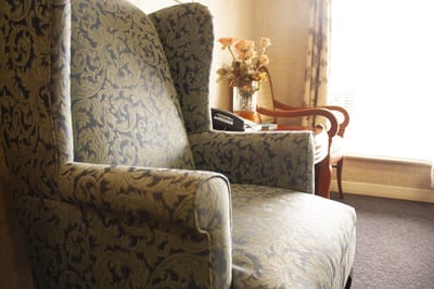 Cozy armchair in a resident's room with floral decor.
