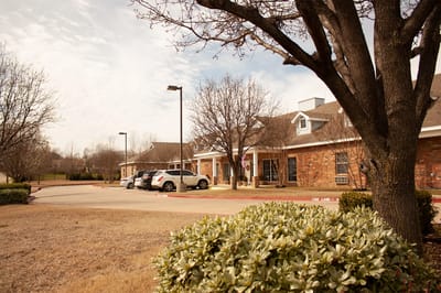 Exterior view of assisted living facility with trees.