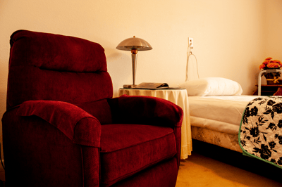 Cozy resident room with a chair and bed.