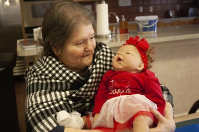 Senior woman holding a baby doll in a caring moment.