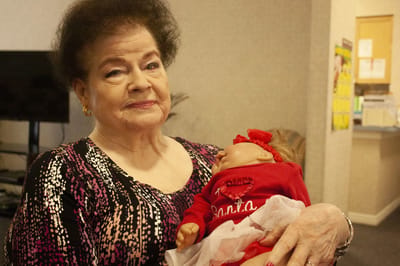 Resident holding a doll in a cozy room.