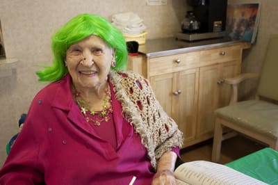 Elderly woman with bright green wig in common area