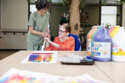 Staff assisting a resident with art activities