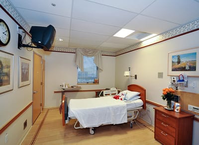 Patient room with a bed and wooden furniture