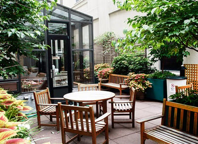 Outdoor seating area with wooden chairs and plants.