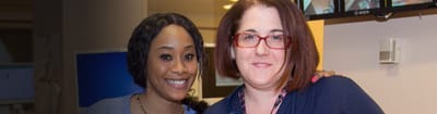 Two staff members smiling together in a facility setting.