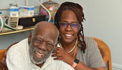 Elderly man smiling with a caregiver in a welcoming interior
