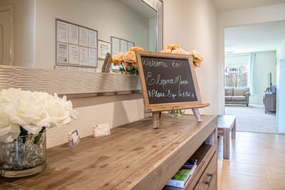Welcoming reception desk with flowers and a sign.