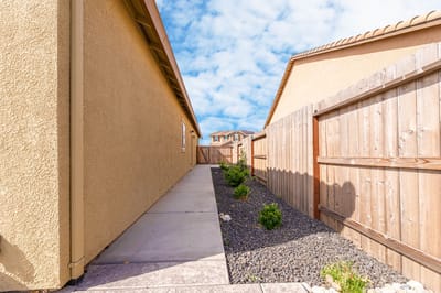 Narrow walkway between two buildings with a fence.
