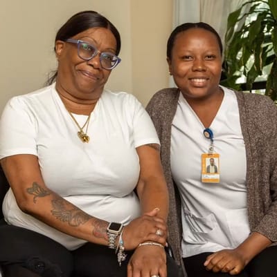 Two staff members smiling together in a bright room.