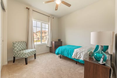Bright and tidy resident room with bed and chair.