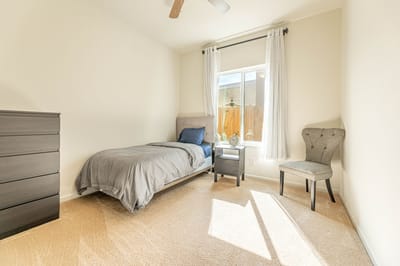 Cozy private room with a bed and chair.