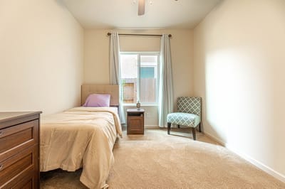 A cozy private resident room with a bed and chair.