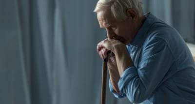 An elderly man resting with a cane