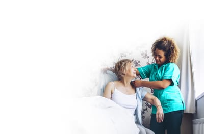 Caregiver assisting a senior woman in a comforting setting.