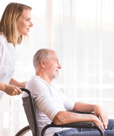 Caregiver assisting a senior man in a wheelchair.