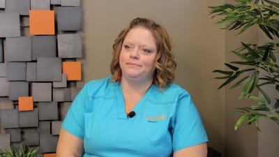 Staff member in a blue uniform sitting indoors.