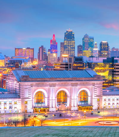 A city skyline at twilight with illuminated buildings.