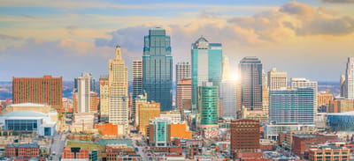City skyline with tall buildings and a sunset.