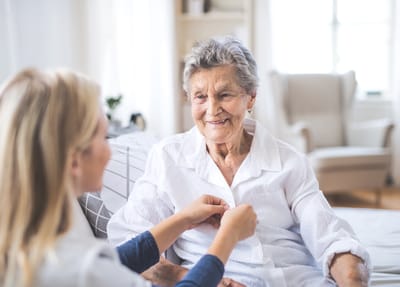 Healthcare provider assisting an elderly woman at home.